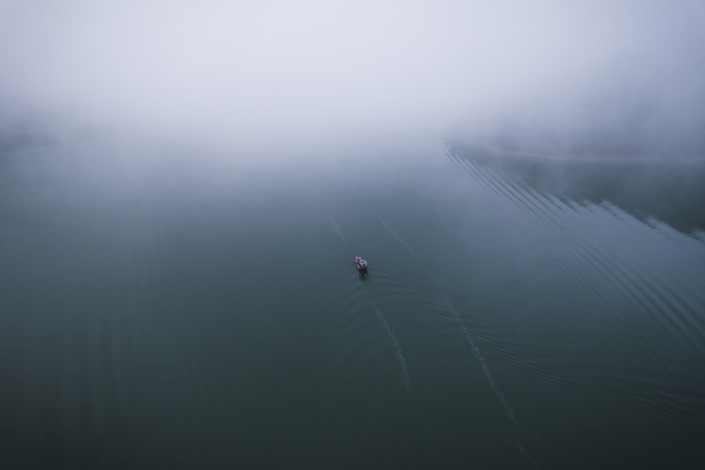 a lone boat in the middle of a foggy river