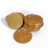 A collection of shiny, gold-colored coins featuring a prominent Bitcoin symbol on each. The coins are stacked and scattered on a white background.