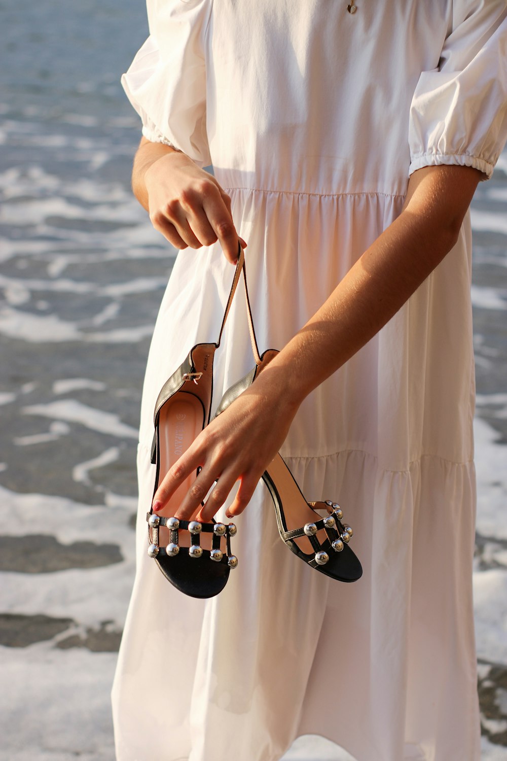 a woman in a white dress holding a pair of shoes