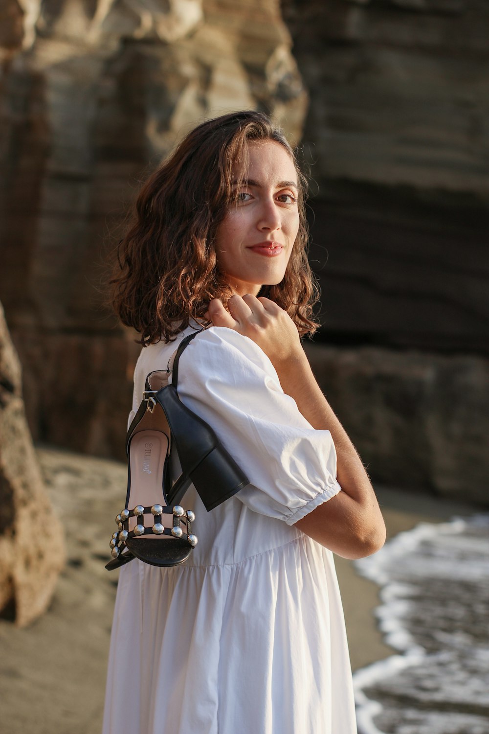 a woman in a white dress holding a black purse