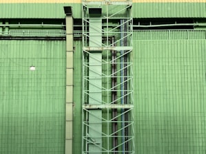 a tall green building with a clock on it's side