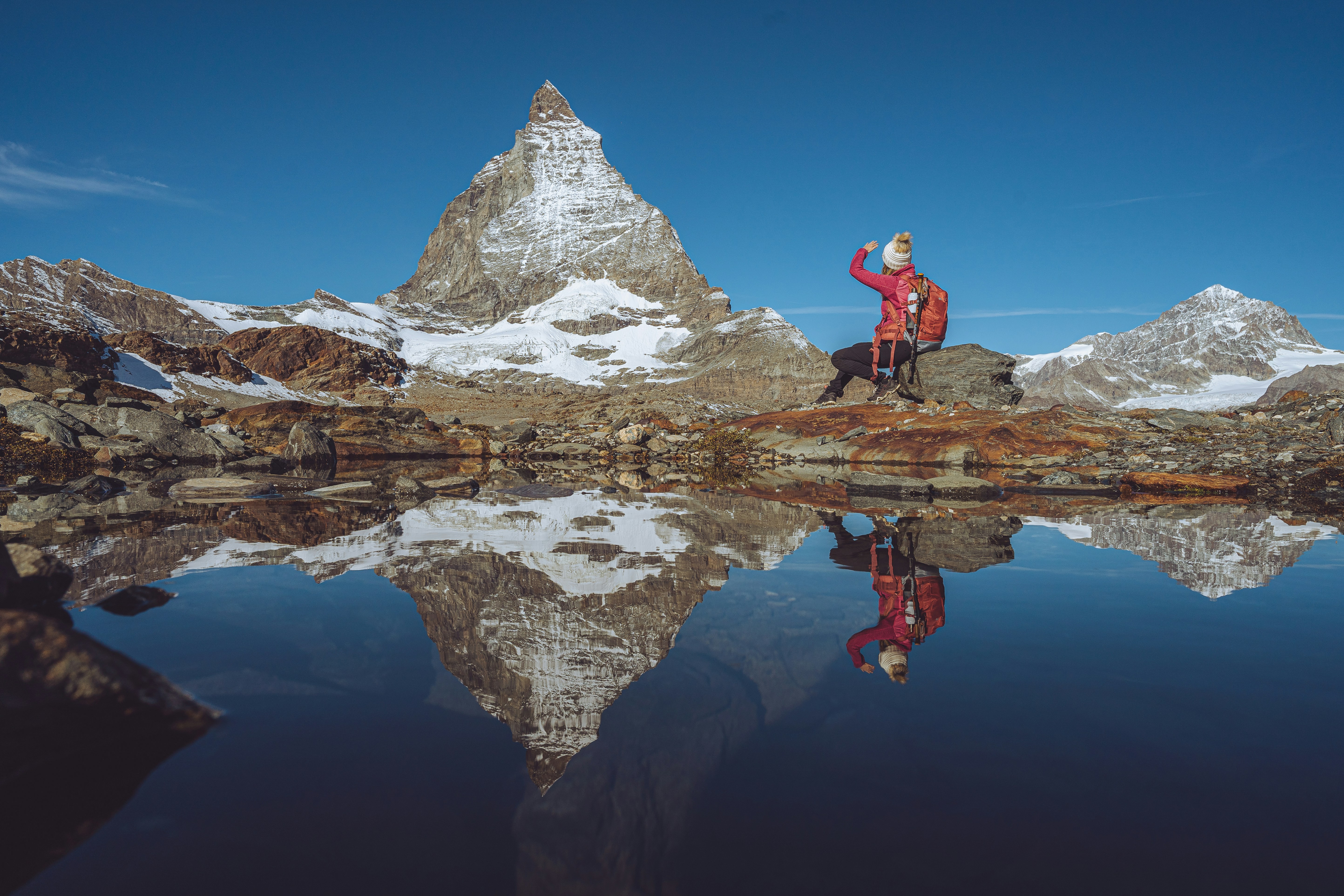 a man standing on top of a mountain next to a lake