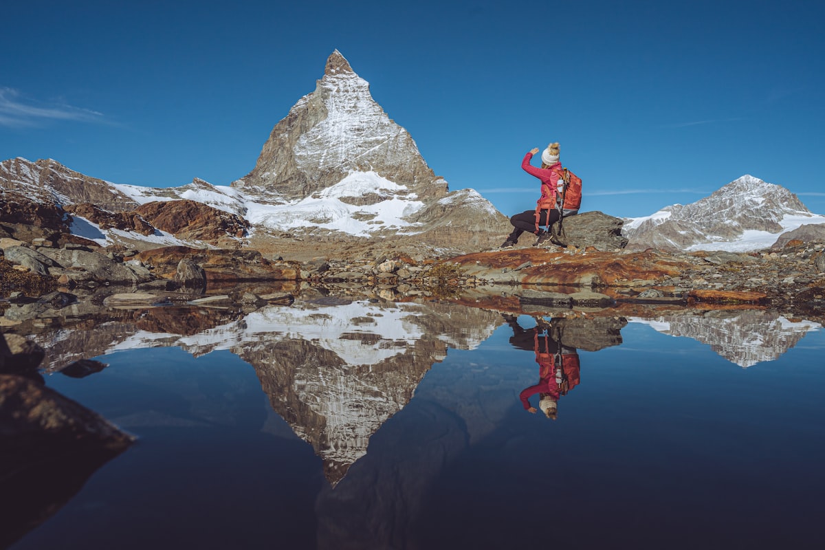 A man standing on top of a mountain next to a lake