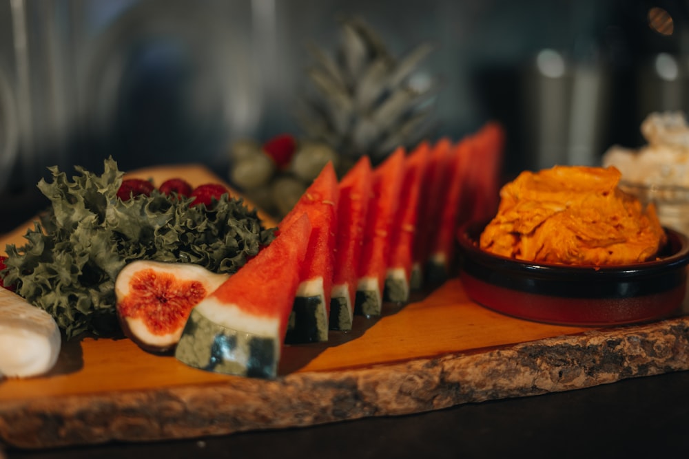 a wooden table topped with slices of watermelon and other fruits