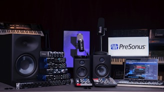 a desk with a keyboard, monitor, speakers and a microphone