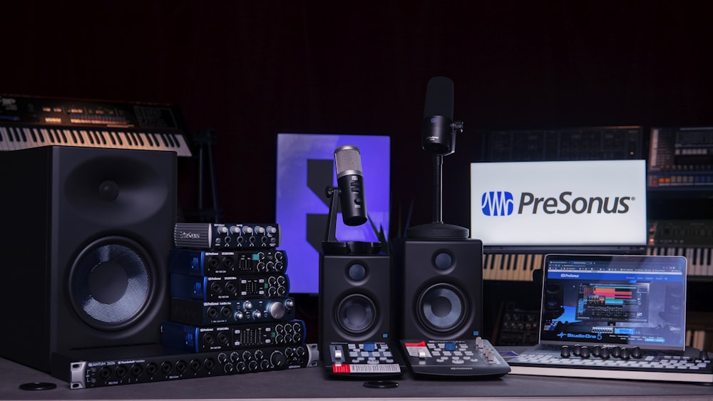 a desk with a keyboard, monitor, speakers and a microphone