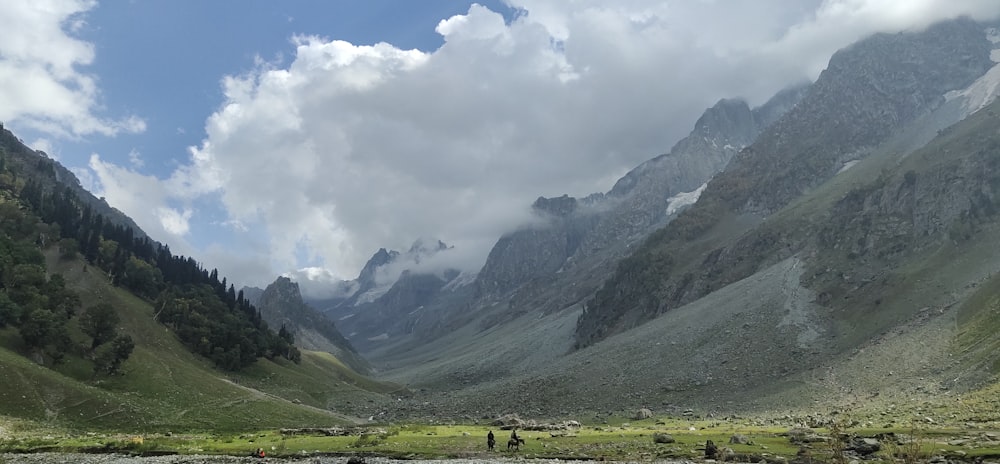 a group of people standing in a valley with mountains in the background