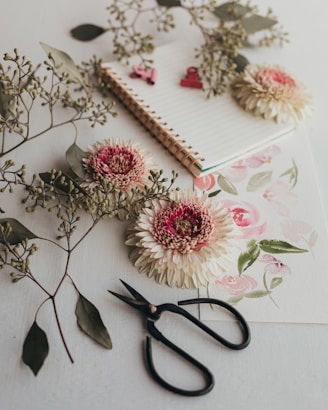 a pair of scissors sitting on top of a table next to flowers