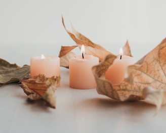 Candles with autumn leaves and warm colors on a rustic background.
