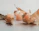 A softly glowing beeswax candle nestled among dried autumn leaves on a dark wooden surface.