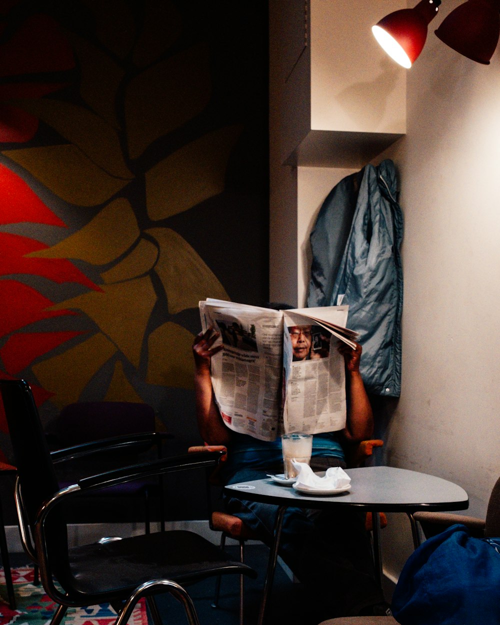 a man sitting at a table reading a newspaper