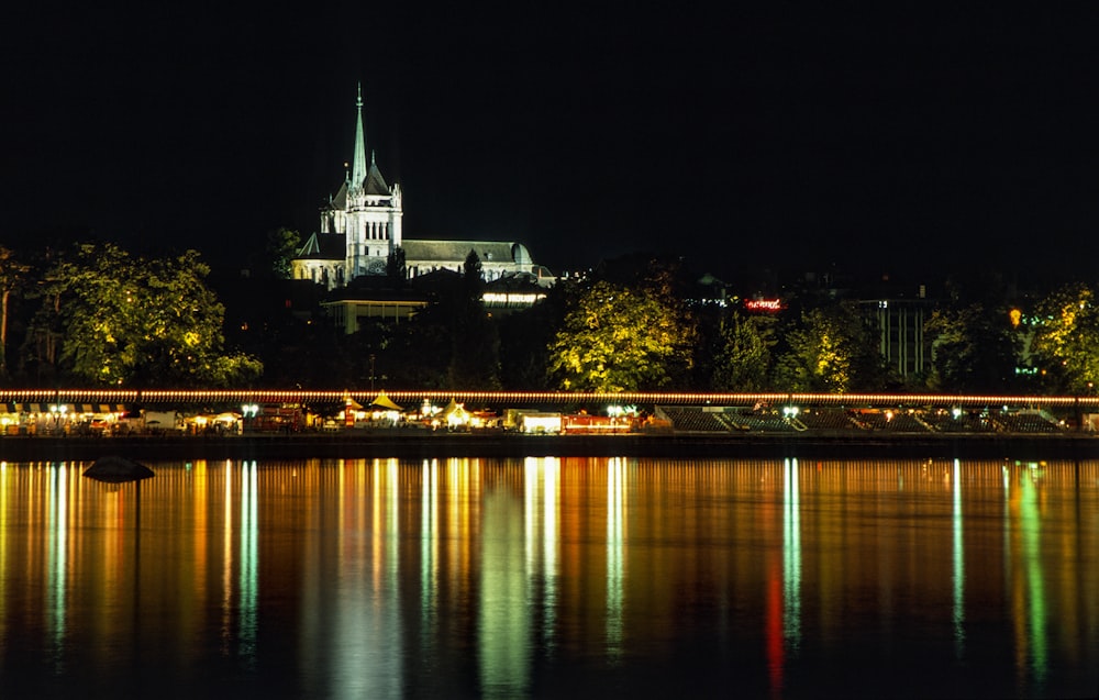 a large cathedral lit up at night over a body of water