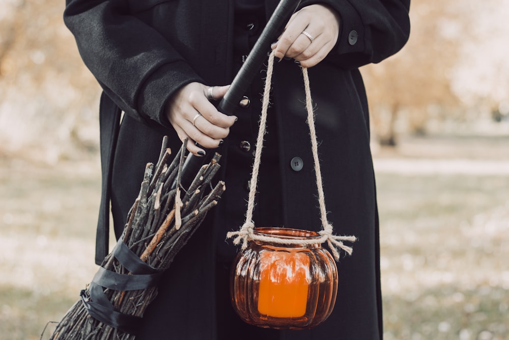 a woman in a black coat holding a pumpkin jar