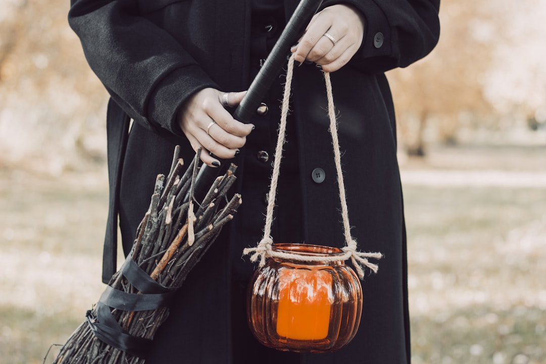 a woman in a black coat holding a pumpkin jar,