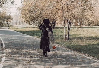 a woman in a black dress is walking down the street