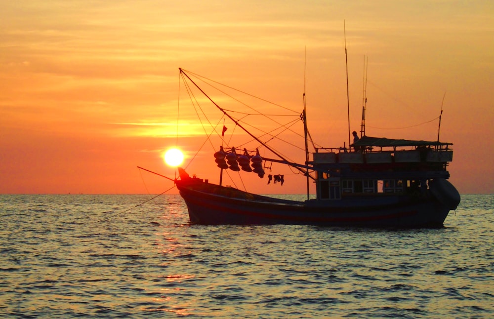 a fishing boat in the ocean at sunset