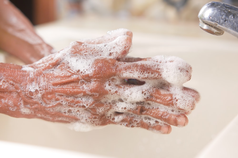 uma pessoa lavando as mãos em uma pia
