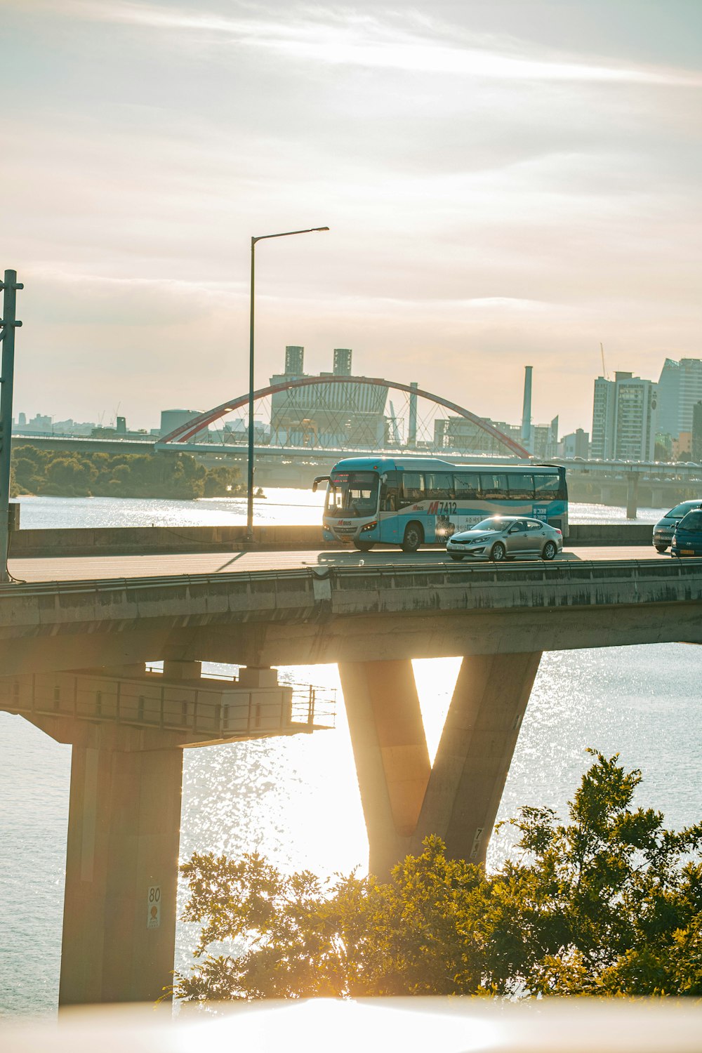 a bus and a car on a bridge over a body of water