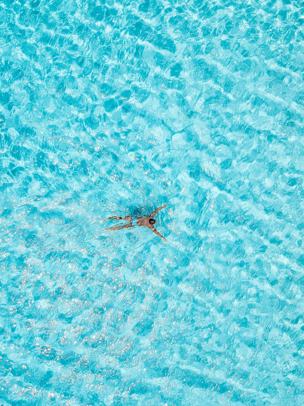 a woman swimming in a pool with a parasol