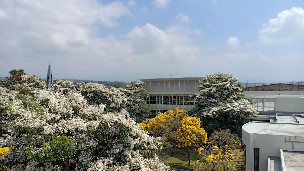 a building surrounded by trees and flowers on a cloudy day