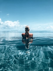a woman is sitting in the water with her back to the camera