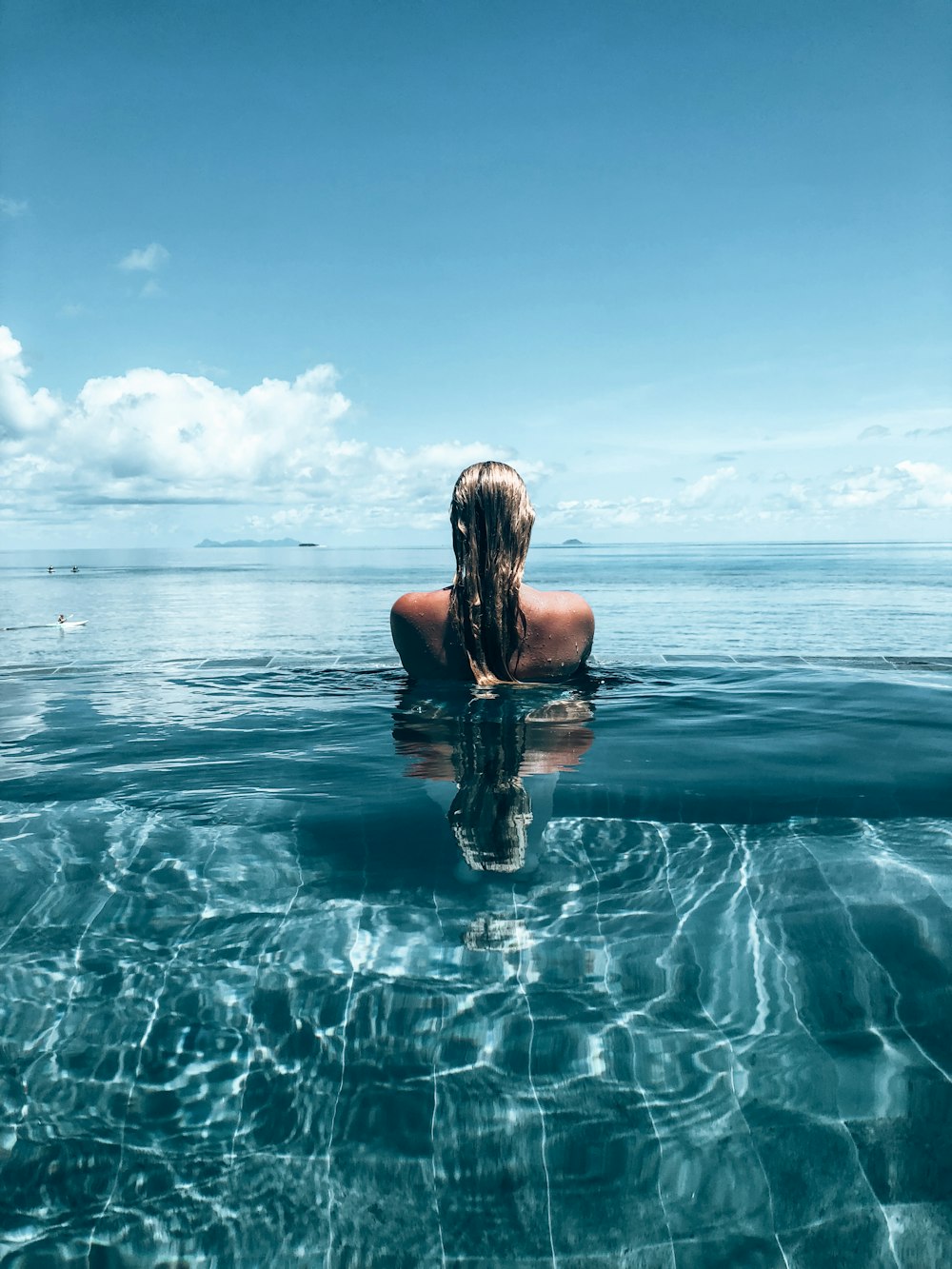 a woman is sitting in the water with her back to the camera