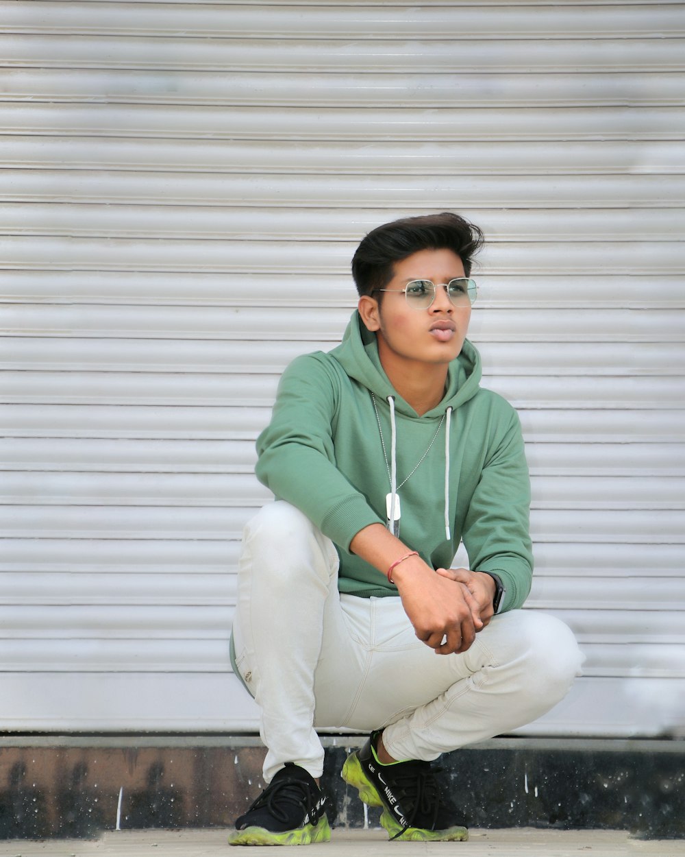 a man in a green hoodie squatting on the ground