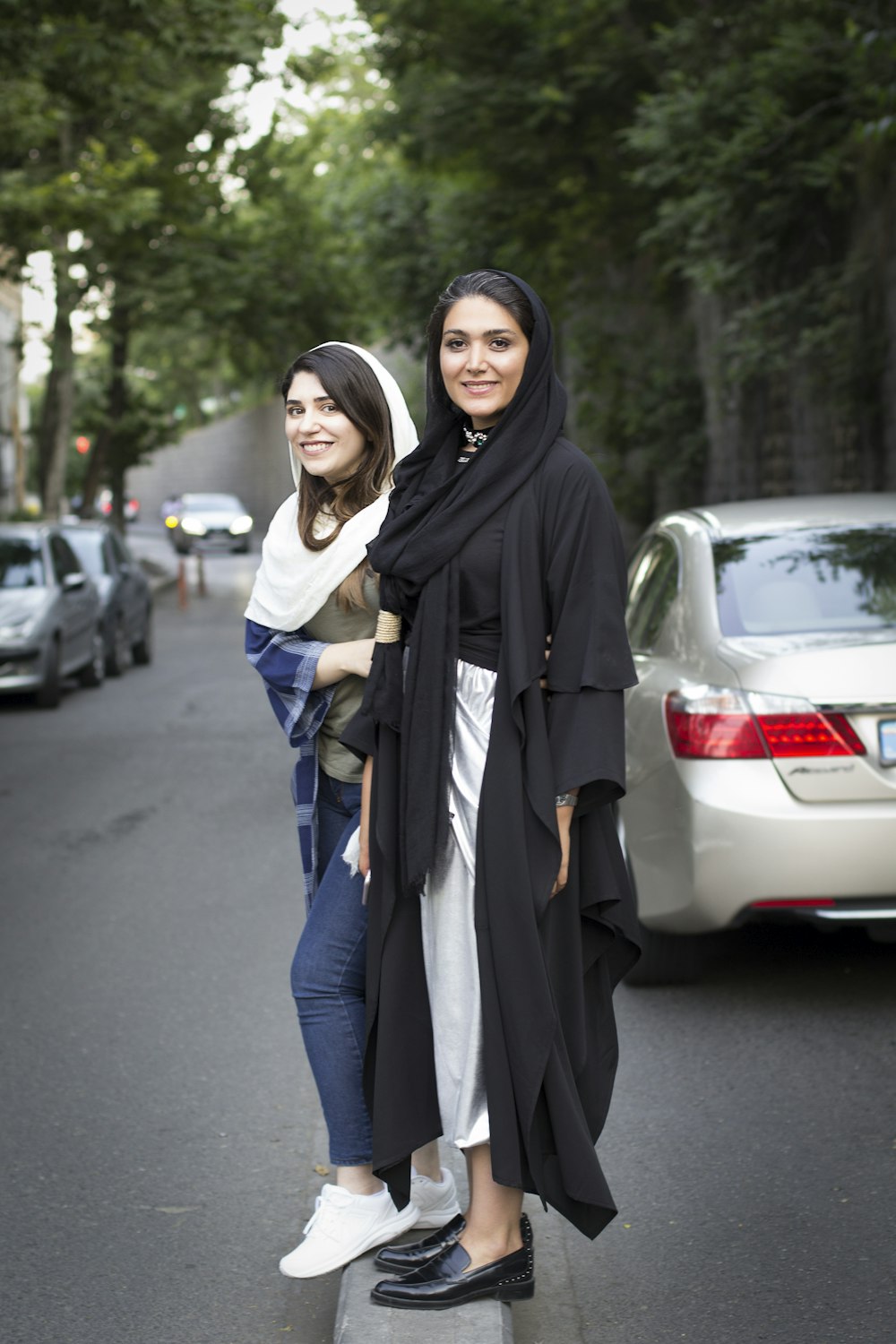 two women standing next to each other on a street
