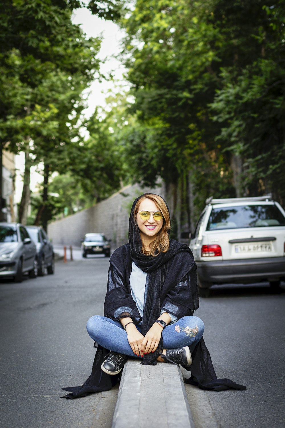 a woman sitting on a curb in the middle of a street