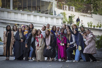 A diverse group of women standing together outdoors, smiling confidently with a city skyline in the background.