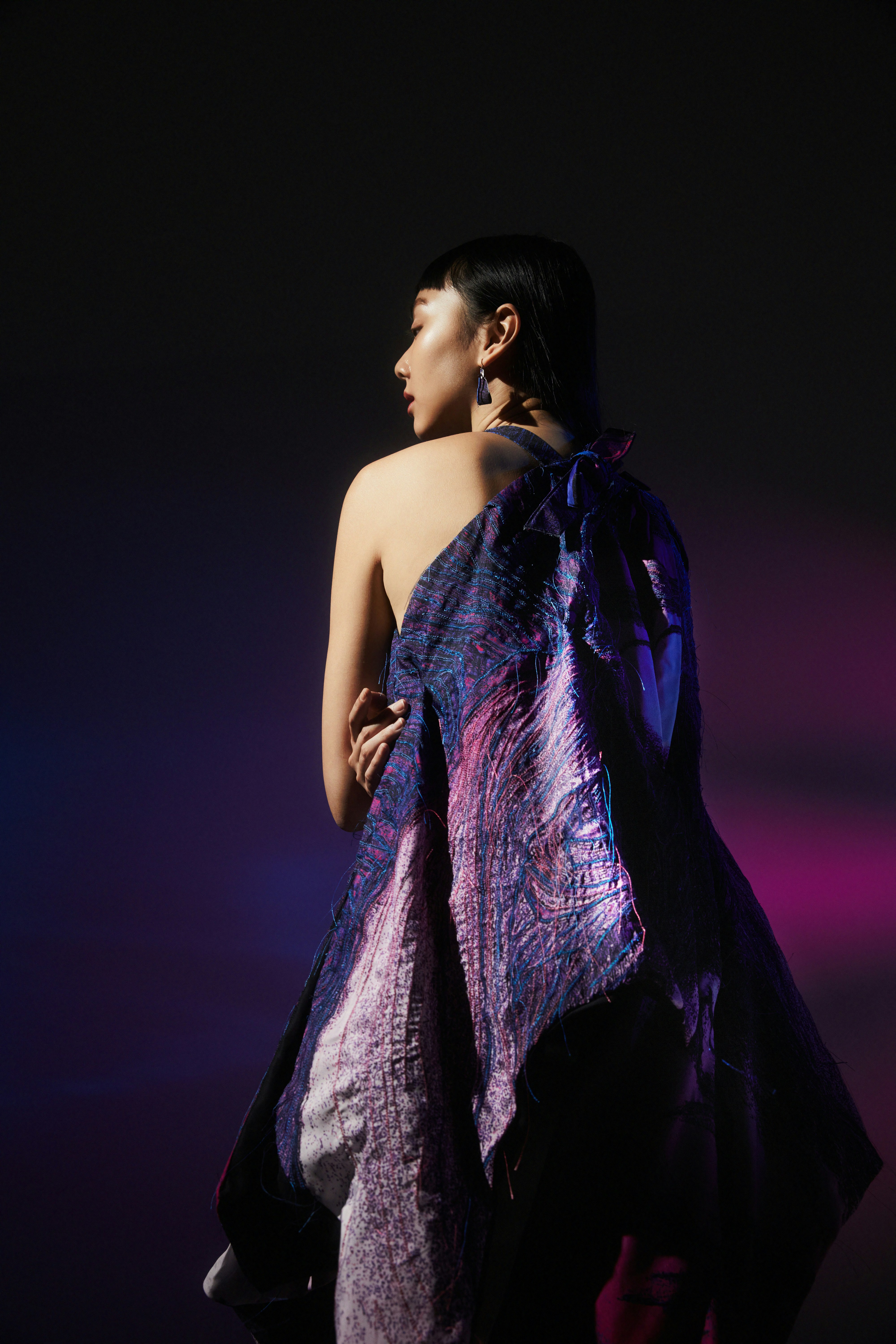 a woman in a purple dress standing in the dark