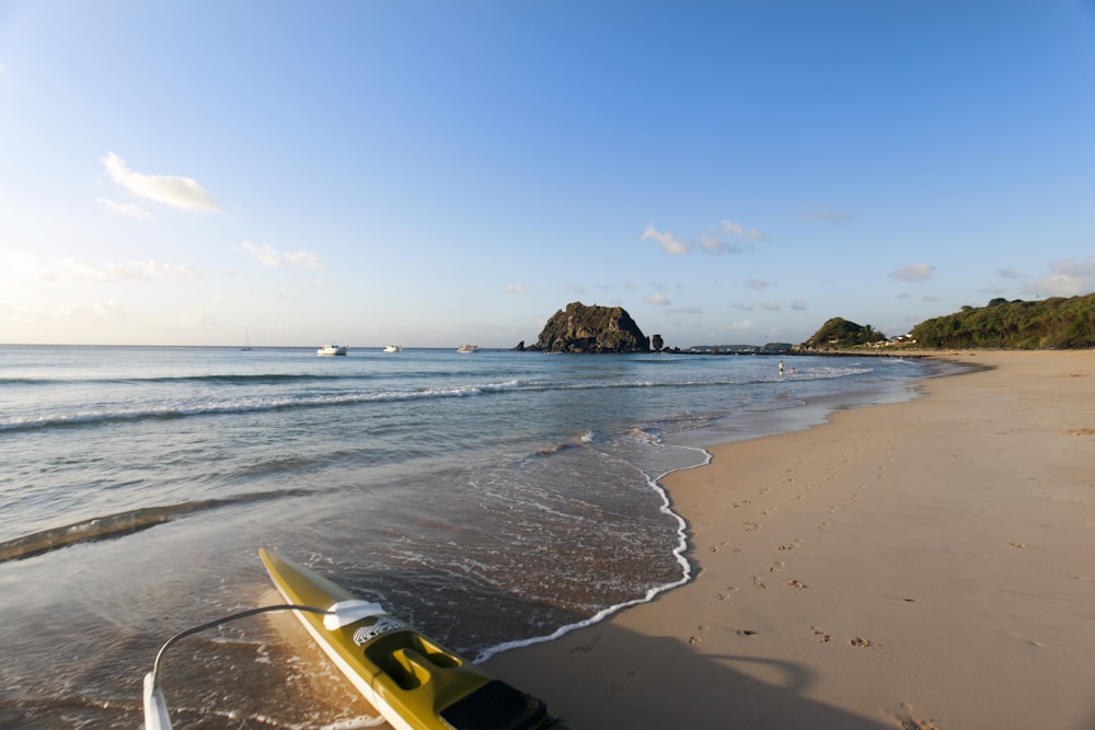 a yellow surfboard sitting on top of a sandy beach