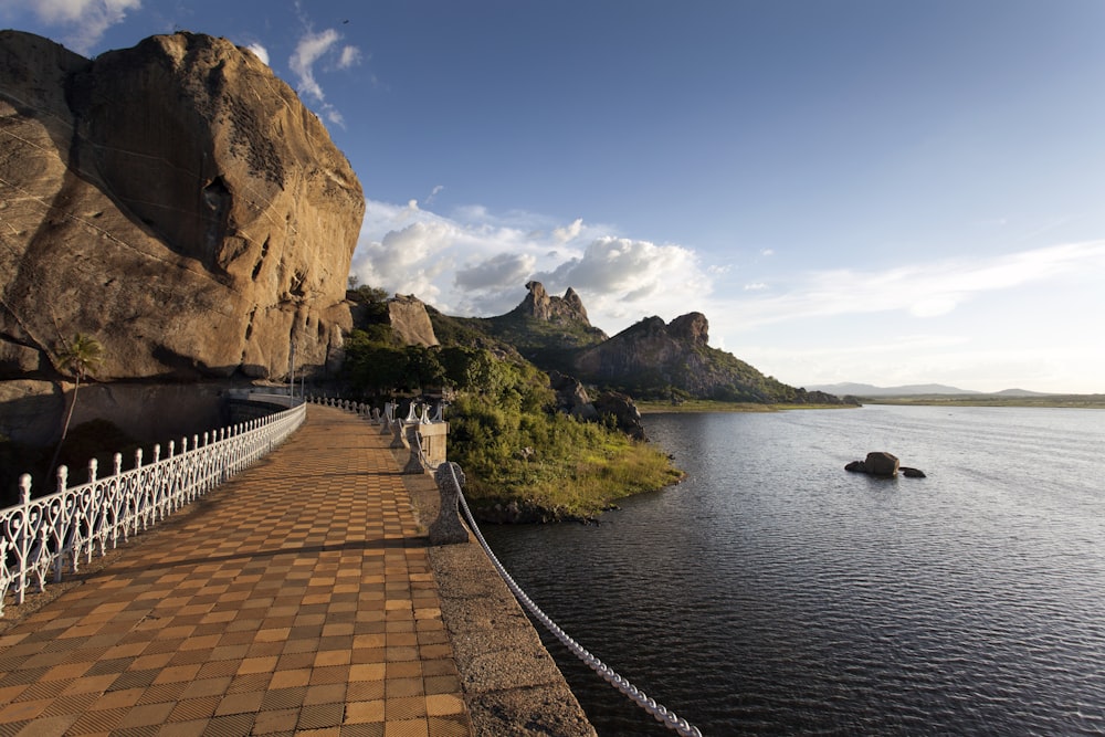 a walkway next to a body of water with mountains in the background