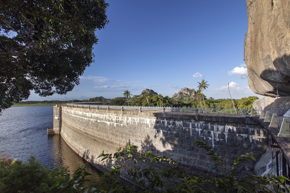 a large stone wall next to a body of water