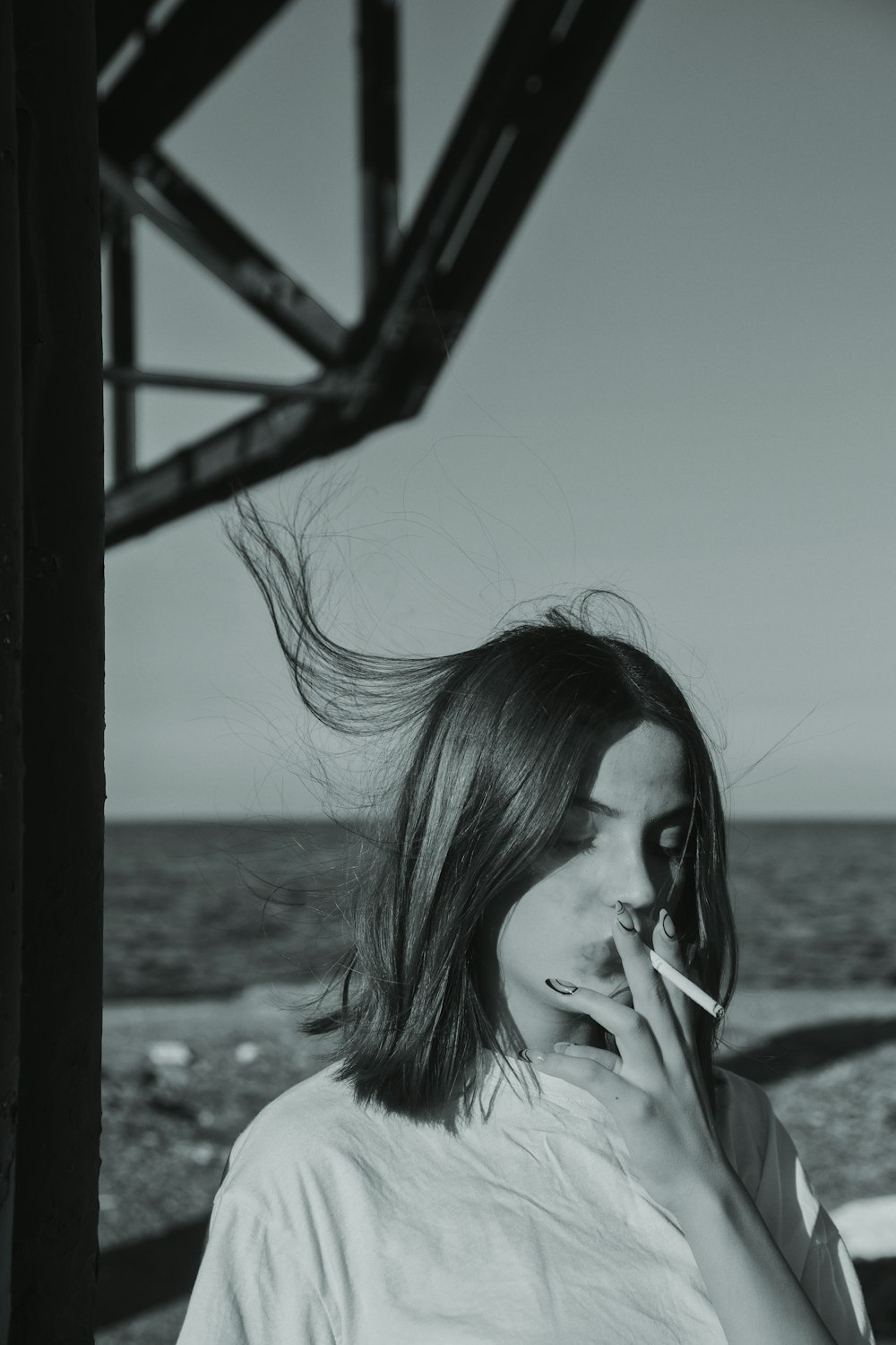 a woman smoking a cigarette near the ocean