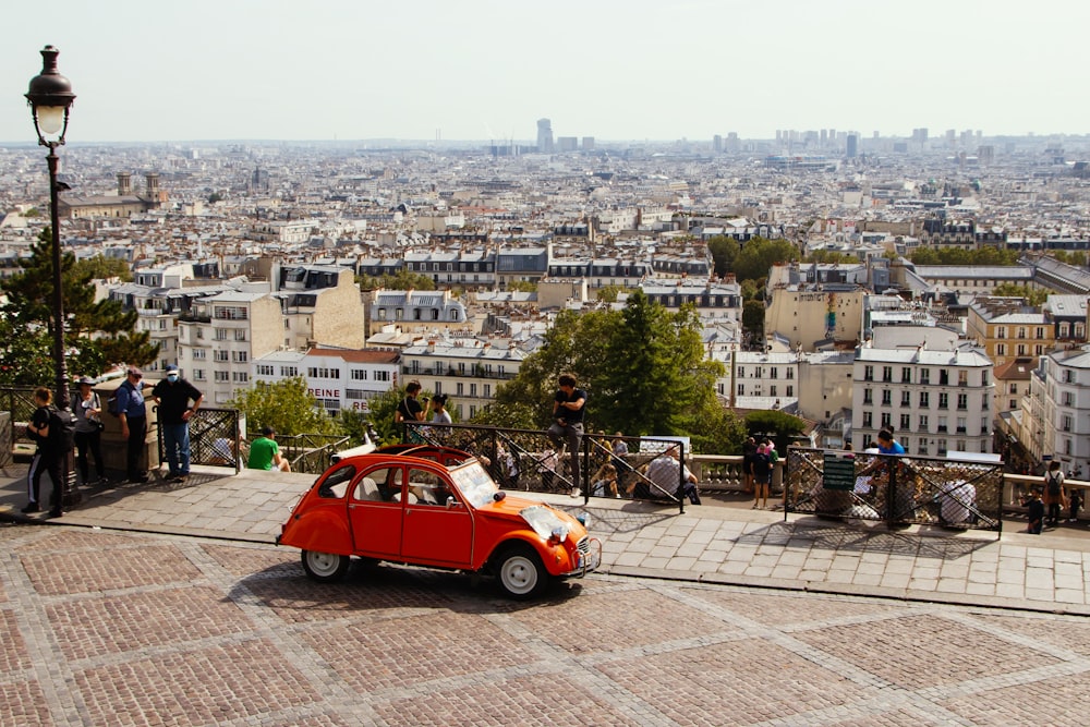 a small red car parked in front of a city