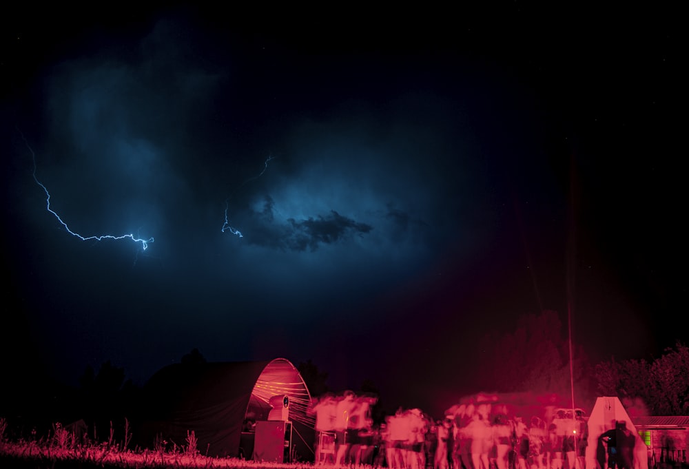 a group of people standing in a field under a dark sky