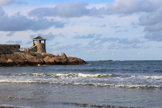 a small tower sitting on top of a rock next to the ocean