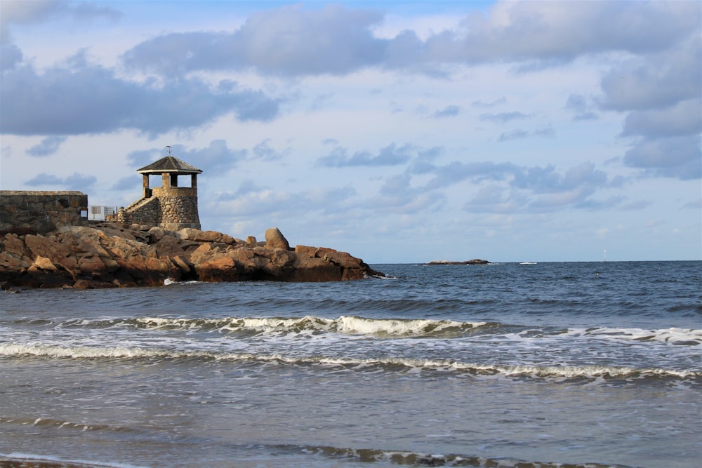 a small tower sitting on top of a rock next to the ocean