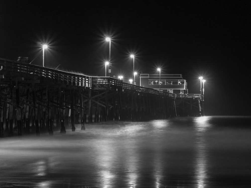 a black and white photo of a pier at night