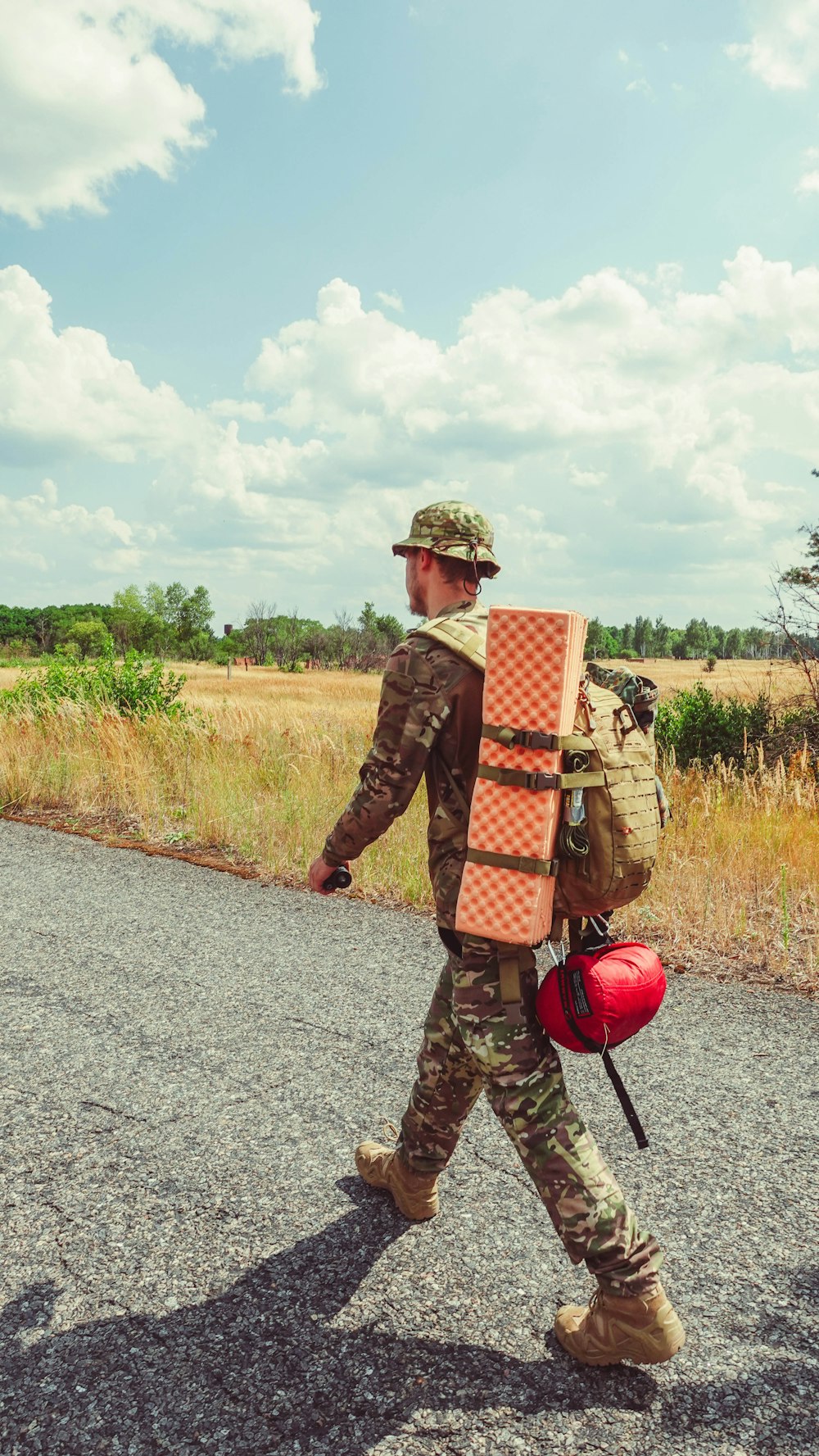 a man walking down a road carrying a surfboard