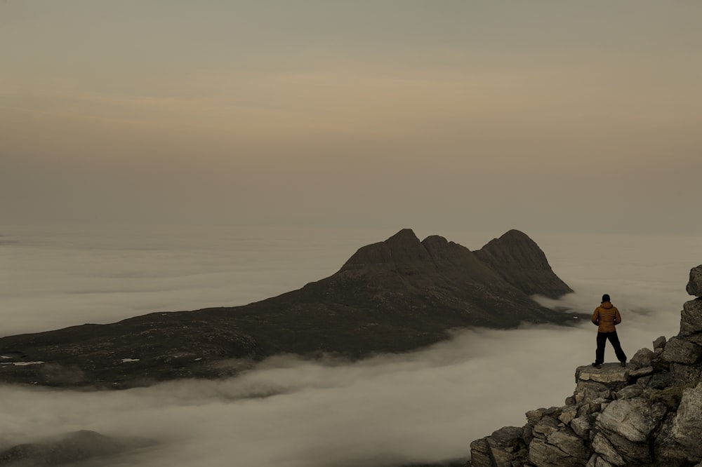 a man standing on top of a mountain above the clouds