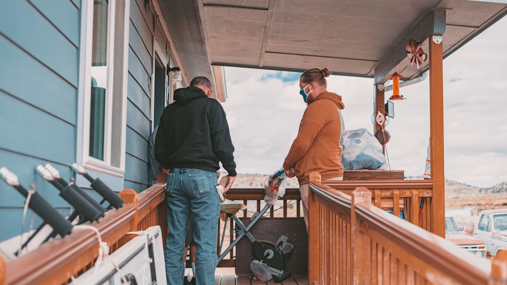 a couple of men standing on top of a wooden porch