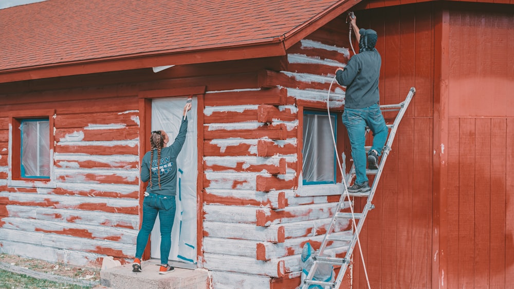 a man standing on a ladder next to a woman