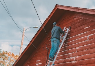 a man on a ladder painting the side of a building