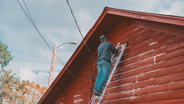 a man on a ladder painting the side of a building