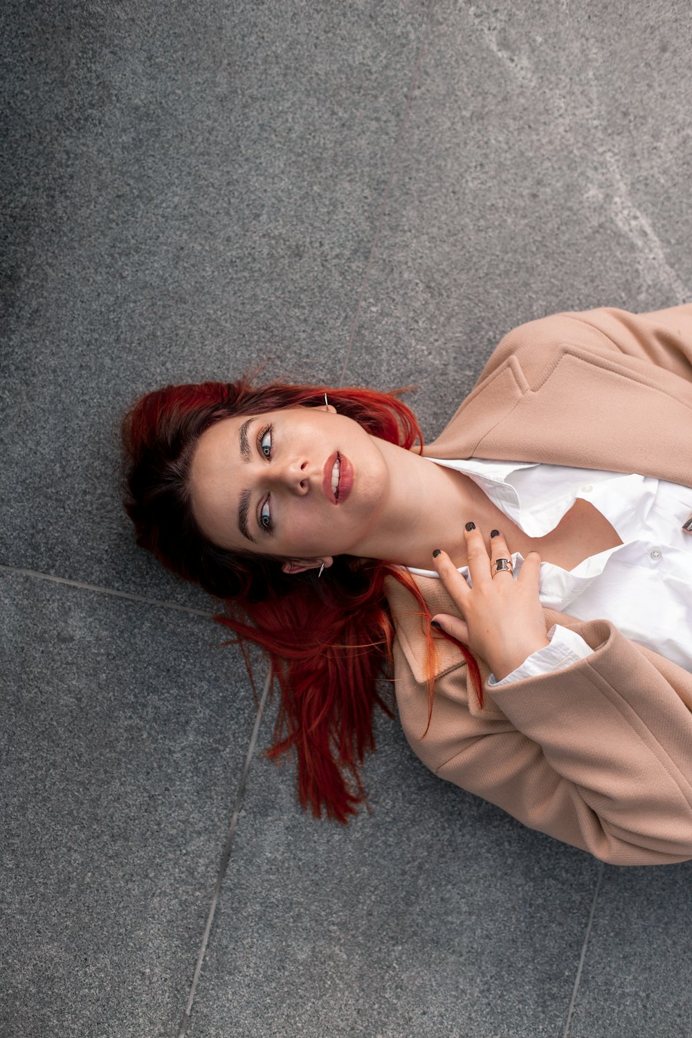 a woman with red hair is laying on the ground