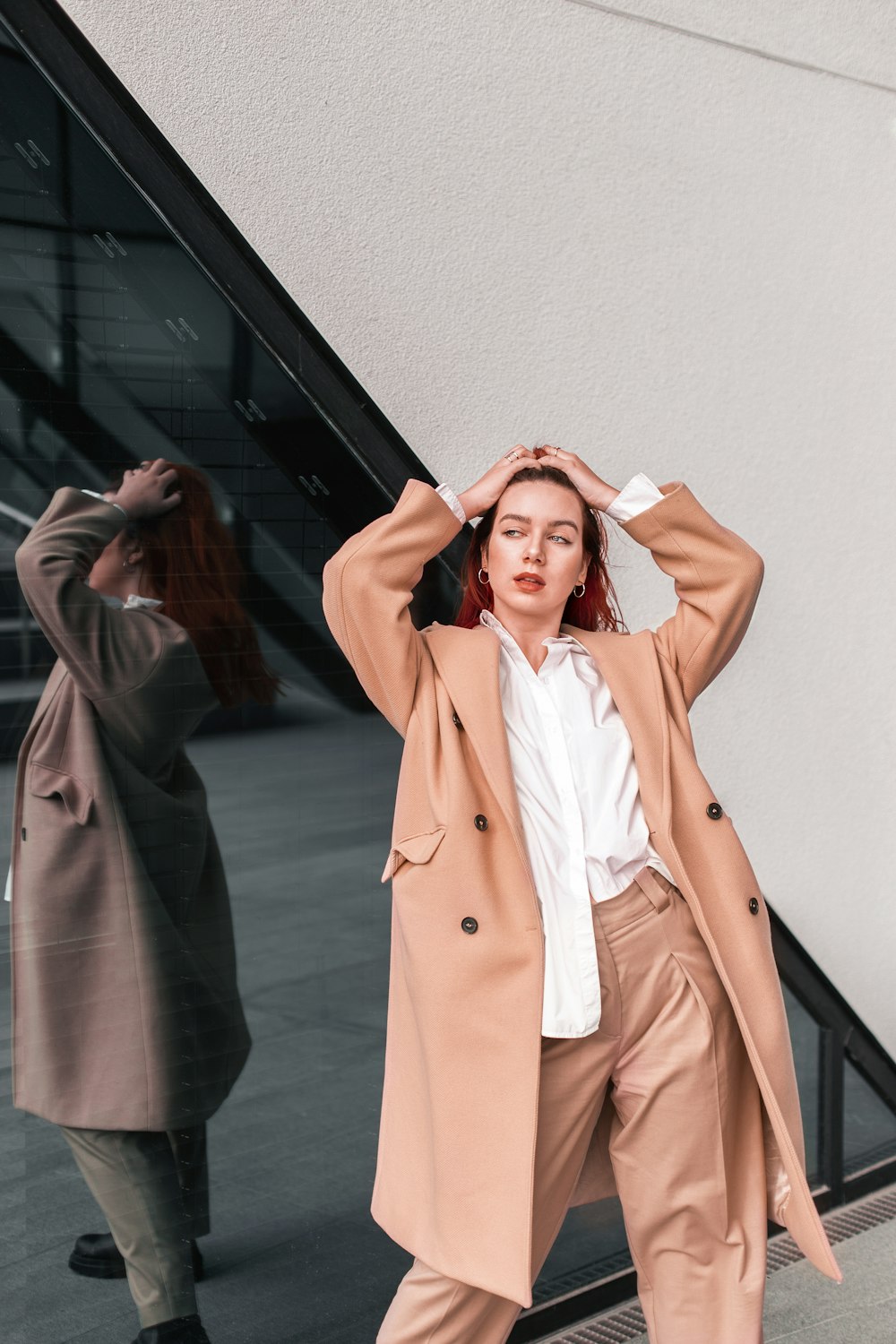 a woman standing next to a wall with her hands on her head