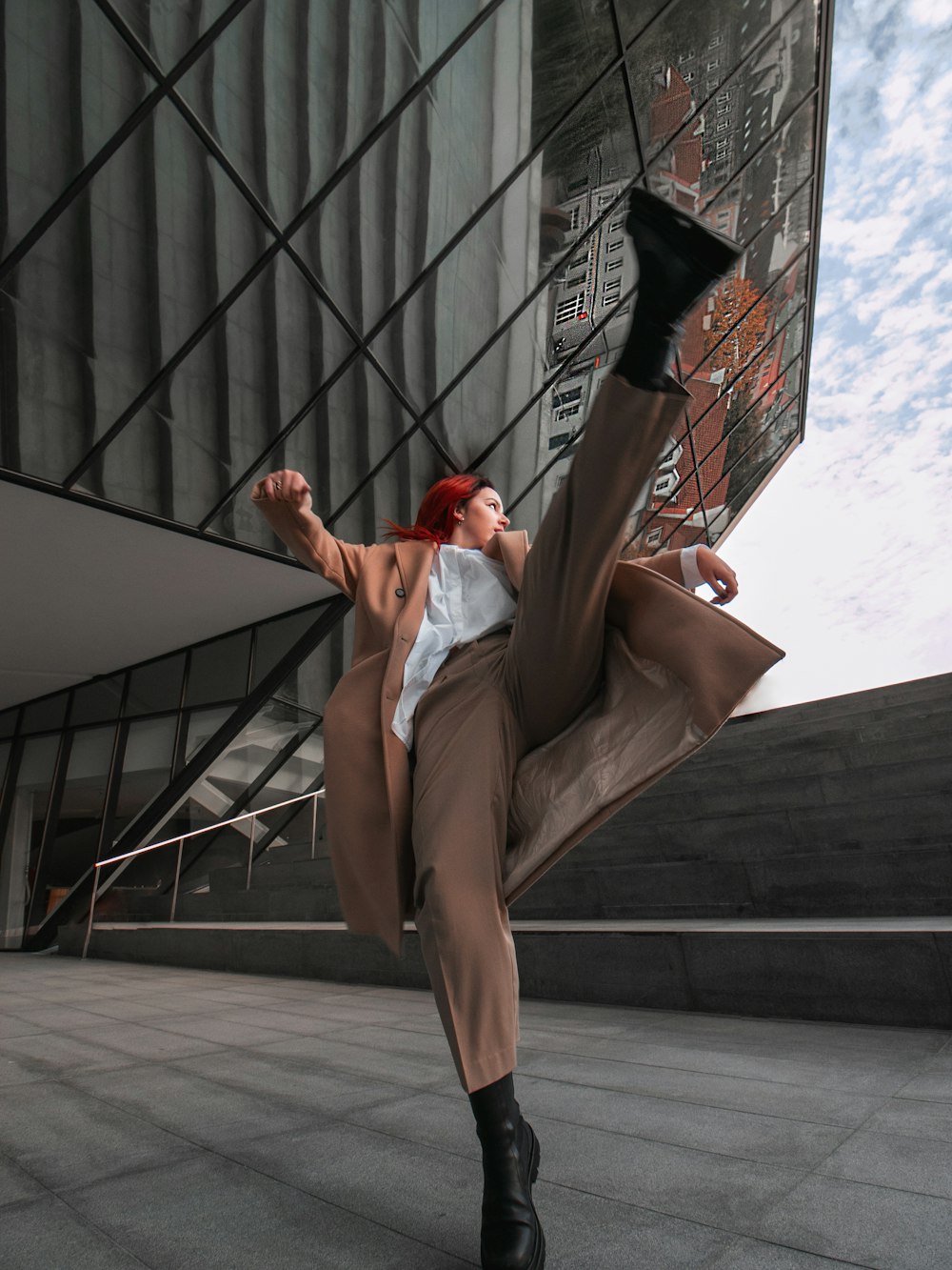 a woman with red hair and black boots is doing a trick