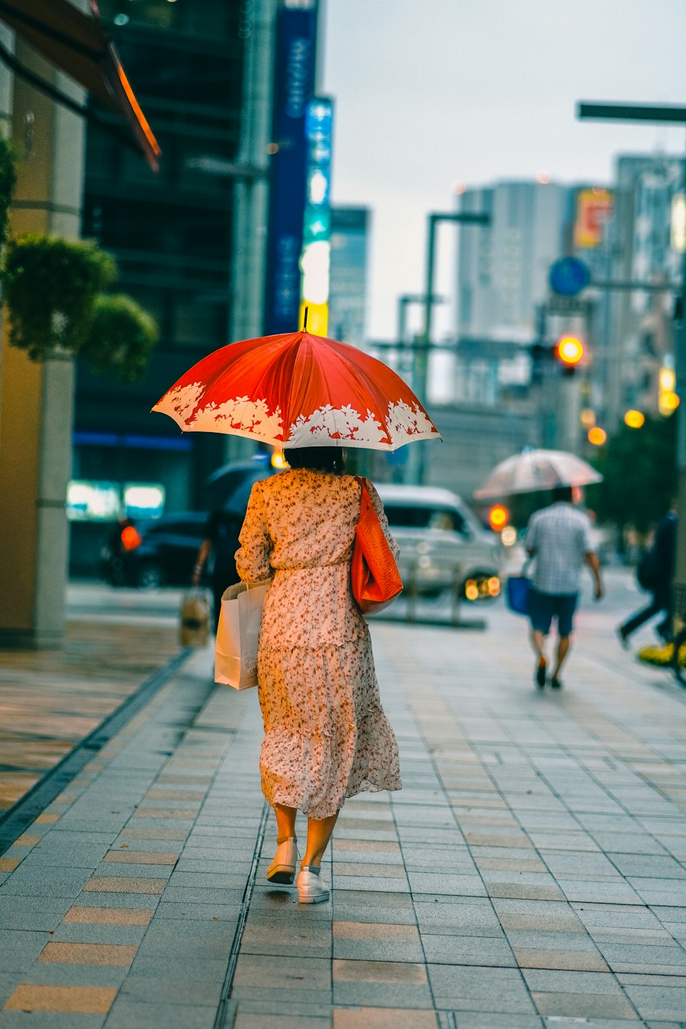 uma mulher andando por uma rua segurando um guarda-chuva
